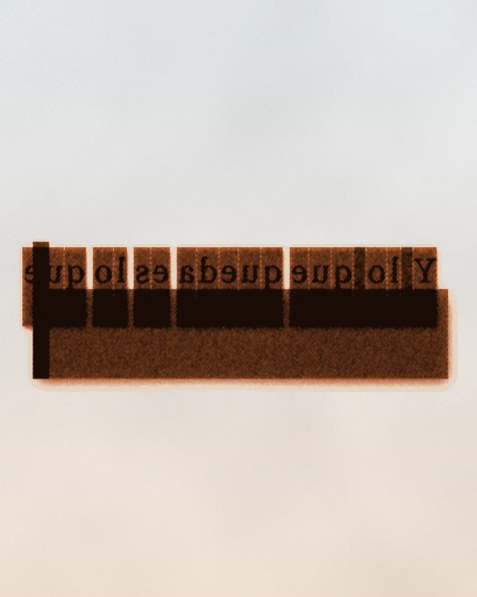 Metal type set in a composing stick. A line of reversed letters has a solid quad in some of its word spaces, so those words cannot part. It is printed in black and an orange ink.