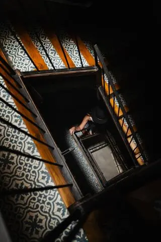 Barcelona, 2024. A dark spiral stairwell over a hydraulic tiled floor.