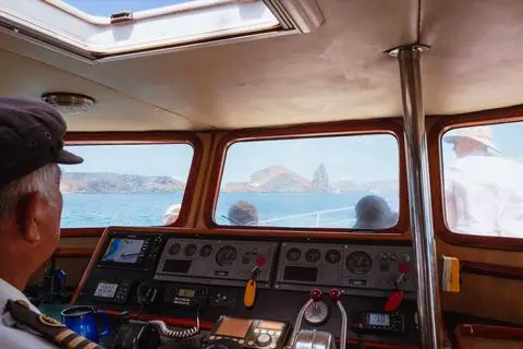 Galápagos, 2024. The captain at the wheel, the islands through the windscreen.
