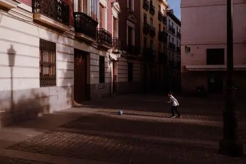 Madrid, 2024. A child kicking a blue ball across an empty street in low light.