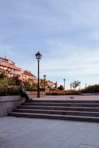 Madrid, 2024. A man sitting by a lamp post above stone steps.