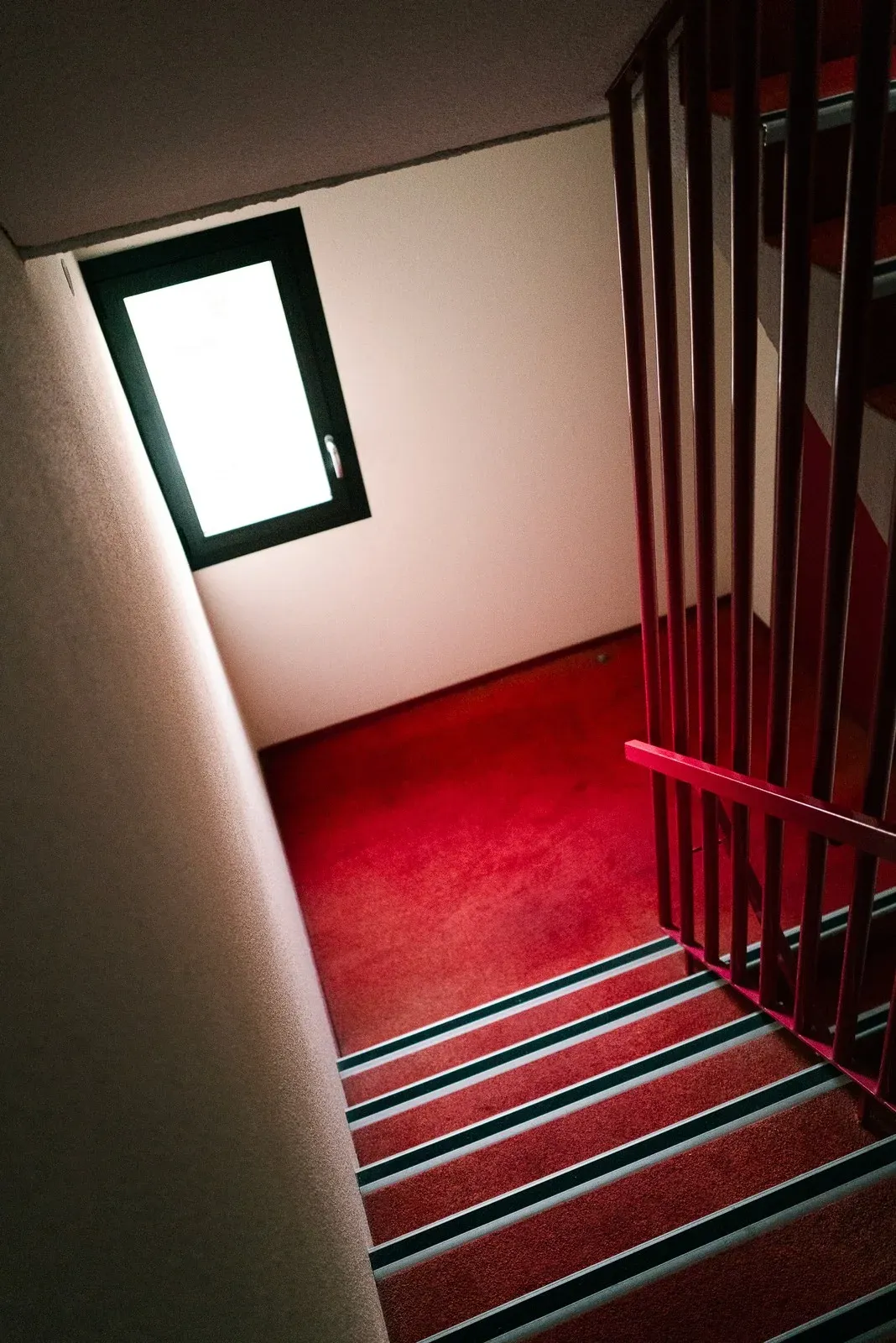 A red stairwell lit by a single window